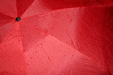 Close up of a wet, red umbrella. Abstract graphic image, suitable for background.
