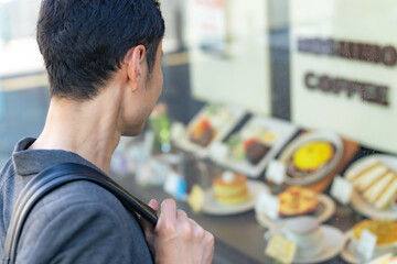 飲食店のショーウィンドウを見る男性