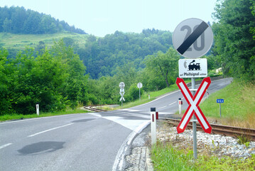 a road with railway crossing and  St. Andrew's cross and two signs