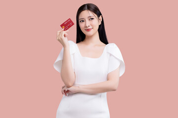 Portrait young Asian woman showing credit card isolated on pink background.