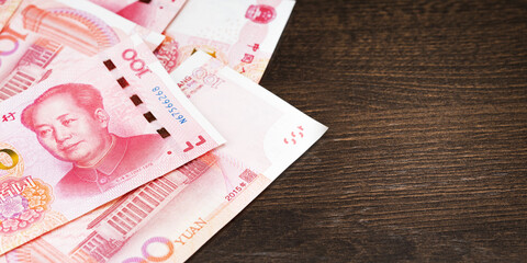 Top view of Chinese Yuan on the dark wooden table with copy space. Horizontal banner.