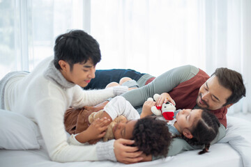 LGBTQ family are Lulling their adopted child to sleep on the bed, LGBTQ couples and adopted children