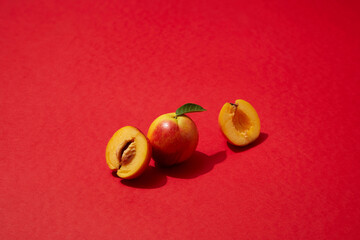 A peach and a peach cut in half are displayed on red plane. Peach (Prunus persica) may help keep your peepers healthy thanks to an antioxidant in peaches