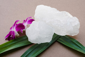 White crystal alum stones or Potassium alum on green leaves. Chemical compound. Useful for beauty...