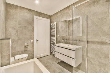 Fototapeta na wymiar a modern bathroom with white fixtures and grey tiles on the walls, along with a freestanding bathtub next to the sink