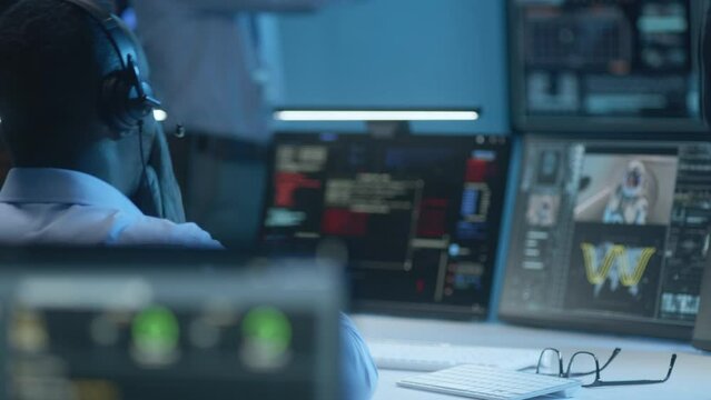 Flight control operators sit in front of computers, monitor space mission in mission control center. Group of workers clap hands after successful spacecraft or satellite launch displayed PC monitors.