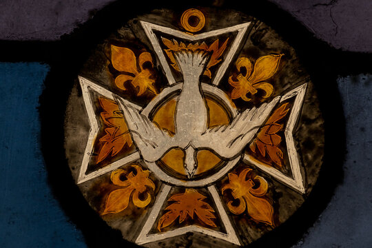 Detail of stained glass panel with gold Maltese cross, white dove, four gold fleur de lys