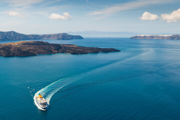 Ferry arrives at the port of Santorini Island, Greece. Blue sea and the blue sky with clouds.
