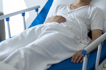 Physiotherapist giving advice and encouragement to male patient doing physiotherapy lying on...