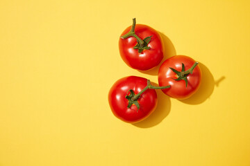 Three fresh tomatoes decorated on a light yellow background. Tomato (Solanum lycopersicum) is packed with vitamins and nutrients that are so advantageous for the skin