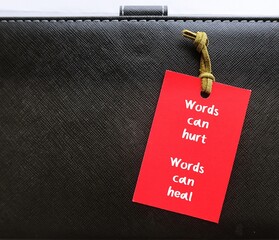 Paper tag with handwritten text Words can hurt Words can heal - to remind language have power to...