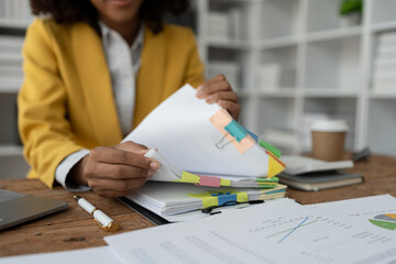 African American businesswoman searching through piles of paperwork for financial, tax, accounting...