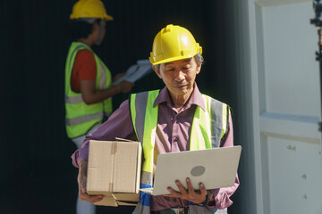 tired asian old senior man holding box and laptop computer . group of two diversity container worker working together with laptop computer in container box at warehouse logistic in Cargo . .