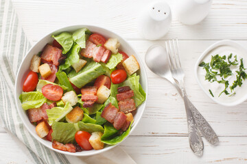 Healthy Organic BLT Bacon Salad with Lettuce and Tomato closeup on the plate on the table. Horizontal top view from above