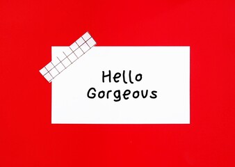 Note stick on  red background with handwritten text HELLO GORGEOUS, nice compliment to make someone...