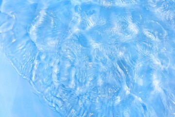 Obraz na płótnie Canvas Blue water with ripples on the surface. Defocus blurred transparent blue colored clear calm water surface texture with splashes and bubbles. Water waves with shining pattern texture background.