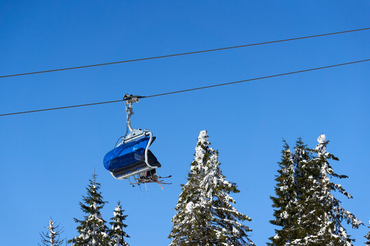 Chairlift of ropeway against blue sky. Cable car transports winter ski and snowboard riders. Ropeway. Germany, Black forest, Feldberg.