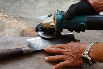 Close up mechanic hands use electric grinders to sharpen iron knife. Concept, traditional style of fixing tool, maintenance tools for cooking, make knife sharp ,not dull for long live using. 