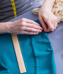Woman tailor working on a clothing sewing stitching measuring fa
