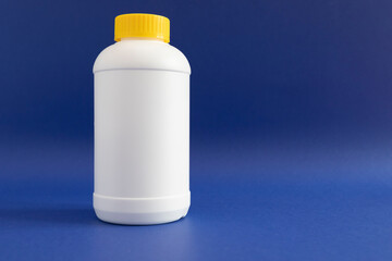 Pipe Unclogging Granules In Yellow Cap, White Plastic Bottle On Blue Purple Background. Acid Drain Cleaner, Housework Help. Horizontal Plane, Copy Space For Text