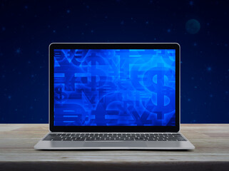 Financial currency symbol on modern laptop computer screen on wooden table over fantasy night sky and moon