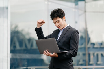 Young Asian business man working at outside business center with laptop, tablet, smartphone  and taking notes on the paper.