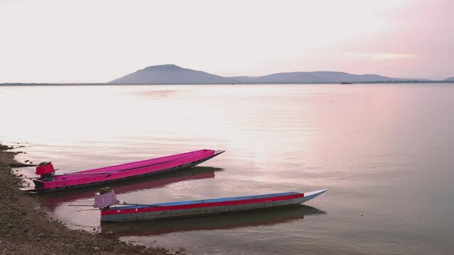 Fishing boats in the river against the backdrop of a beautiful orange sunset setting the mountains.