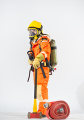 Side view of firefighter stands on a white background using an iron axe on the ground while holding a fire hose in one hand and an oxygen tank behind his back with the other and looking to the camera.
