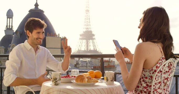 Couple, balcony and breakfast photography in Paris, peace sign and smile for profile picture at table. Young man, woman and social media for travel memory, holiday or love in France, food and terrace