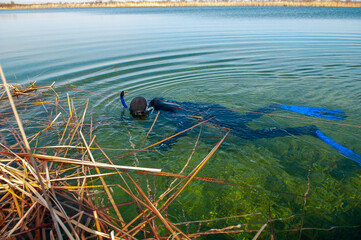 The diver swims in a wetsuit, flippers and a mask with a tube. The rescuer divers carries out work under water.
