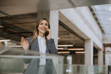 Young business woman using mobile phone in the office hallway