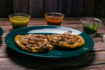 Sope pocho, typical Mexican food served with condiments on a wooden table.