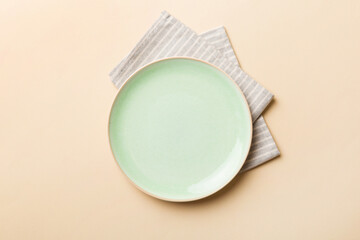 Top view on colored background empty round green plate on tablecloth for food. Empty dish on napkin with space for your design