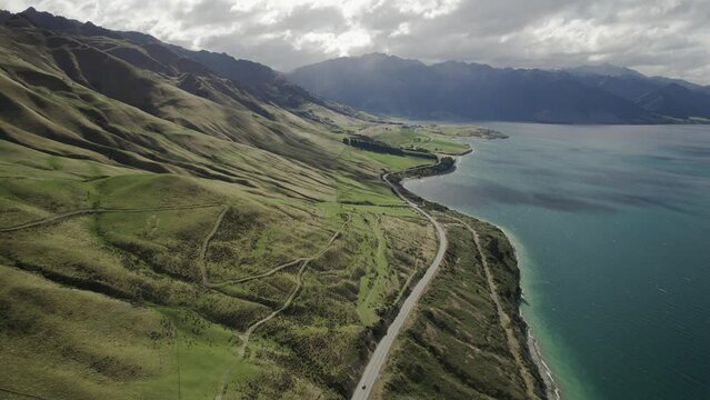 Landscape of a road between mountains and a lake at Lake Hawea, New Zealand.