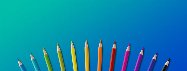 Colored pencil group isolated on blue. Panoramic banner background