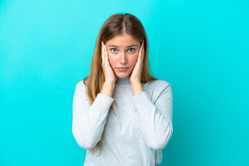 Young blonde woman isolated on blue background frustrated and covering ears