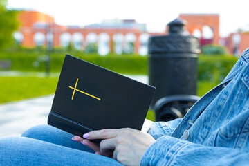 woman reading the bible sitting on a bench