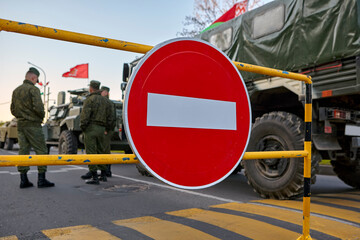 Fototapeta premium Soldiers stand near the car against the background of the STOP sign.