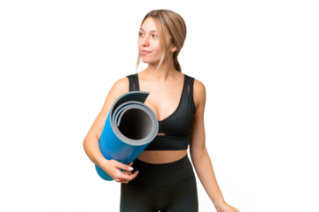 Blonde sport woman going to yoga classes while holding a mat over isolated chroma key background looking to the side