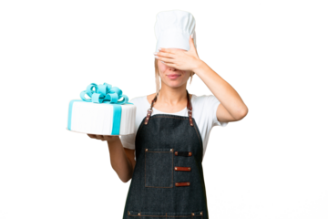 Young pastry blonde woman with a big cake over isolated chroma key background covering eyes by hands. Do not want to see something