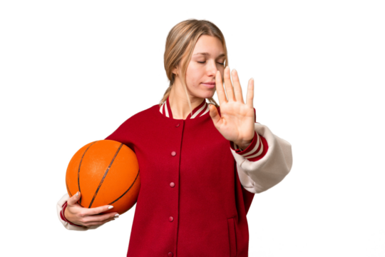 Young hispanic woman playing basketball over isolated white background making stop gesture and disappointed