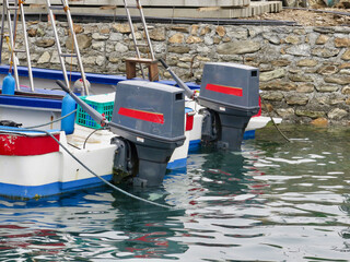 Two boat motors. Boat motors are attached to the stern of boats in the harbor.