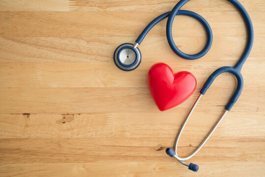 Top view of doctor blue stethoscope and red heart on wooden table background with copy space. Cardiology, world heart health day, heart center in hospital, health medical, life insurance concept.