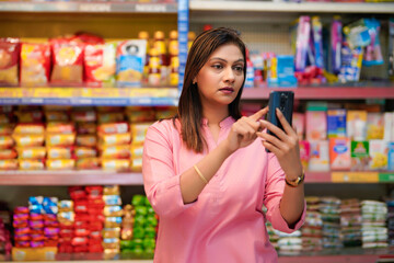 Indian woman using smartphone at super market