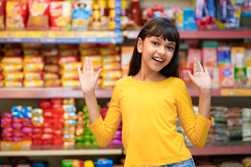 Indian girl giving expression with hand at grocery shop.