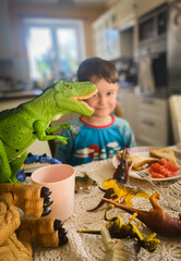 Smiling boy at the kitchen table, eating breakfast with dinosaurs, copy speace
