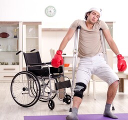 Fototapeta na wymiar Injured young man doing exercises at home