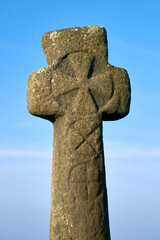 Old stone cross with blue sky behind