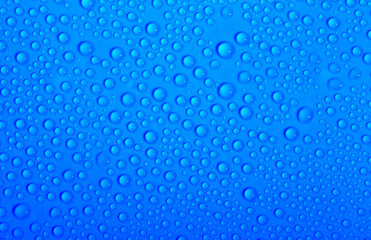 Fototapeta na wymiar Water drops on glass as a background. Condensation on a cold drink. Blue background with drops texture.