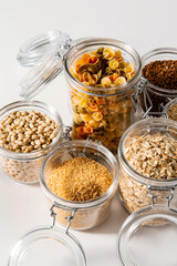 food storage, culinary and eating concept - close up of jars with different cereals, pasta and beans on white background